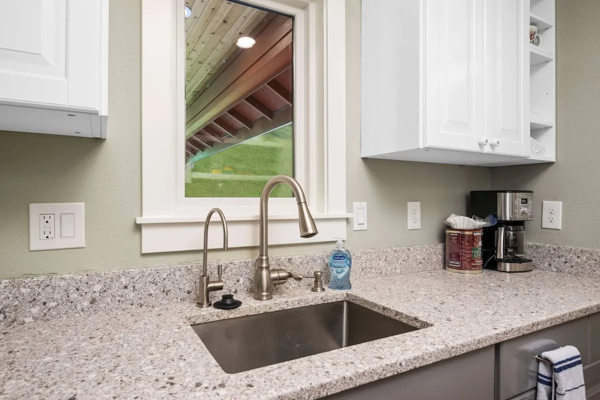A cozy kitchen nook with a sink, window, generous countertop space, and a coffee maker. The inviting scene hints at casual breakfasts or baking days, with natural light streaming in to enhance the welcoming feel of the kitchen.