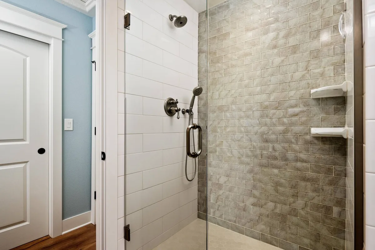 A modern, glass-enclosed walk-in shower with elegant, tiled walls. The bright, clean setting evokes a sense of freshness and rejuvenation, inviting guests to unwind after a long day.