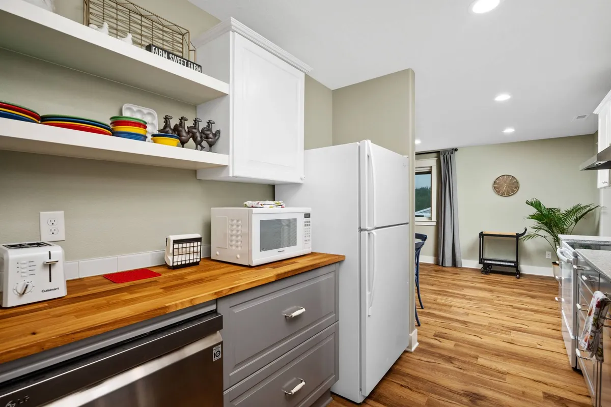 A cozy kitchen space with a wooden countertop, colorful dishware, and modern appliances. The scene feels lively and sociable, inviting guests to gather for meal preparation, coffee, or conversation.