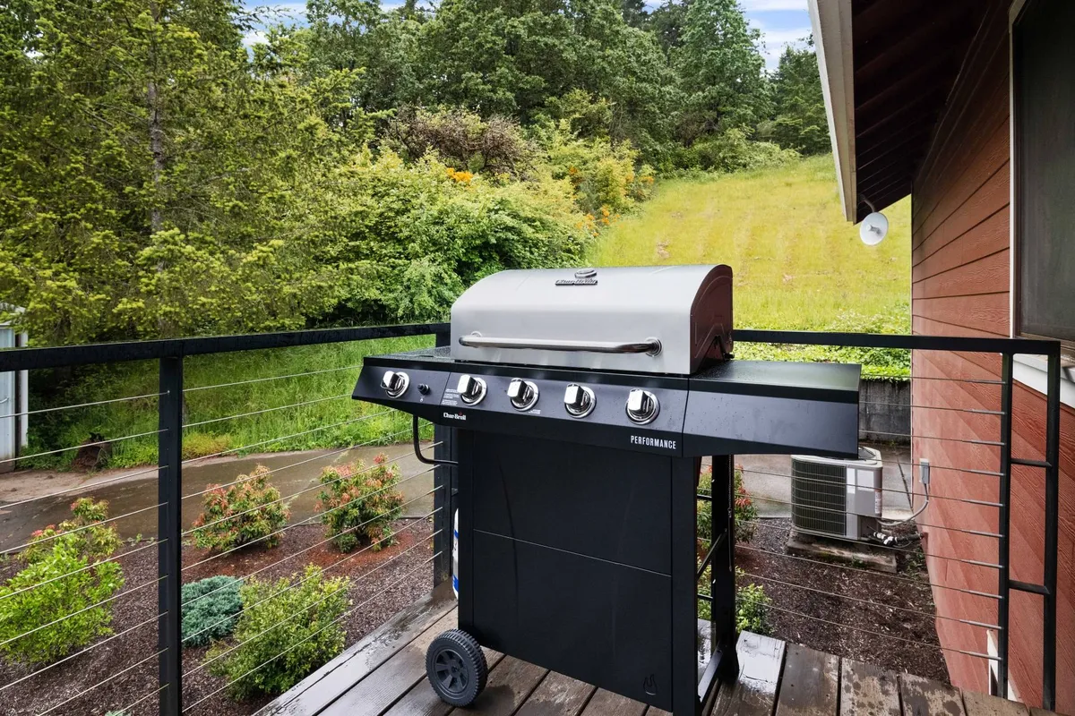 A welcoming deck with a grill, surrounded by greenery and featuring a comfortable space for outdoor dining. The area invites guests to barbecue, dine al fresco, or simply relax as the sun sets over the countryside.