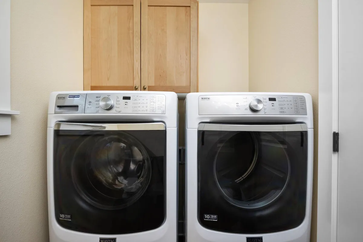 A practical laundry nook with a washer and dryer set into wooden cabinetry, neatly organized for guest use. The space is functional and tidy, offering an added layer of convenience to the home.